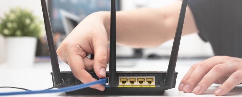 Personne connectant un câble ethernet à un routeur