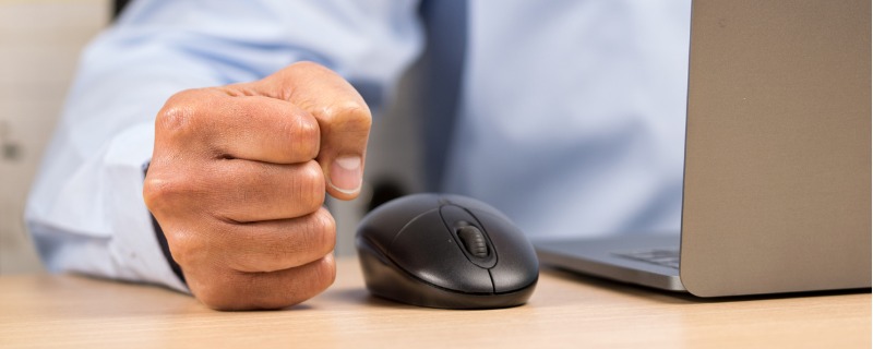 Gros plan sur le poing serré d'un homme a côté d'une souris d'ordinateur