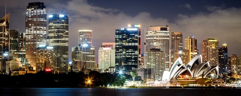 Vue nocturne sur la ville de Sydney avec l'opéra visible sur la droite de l'image