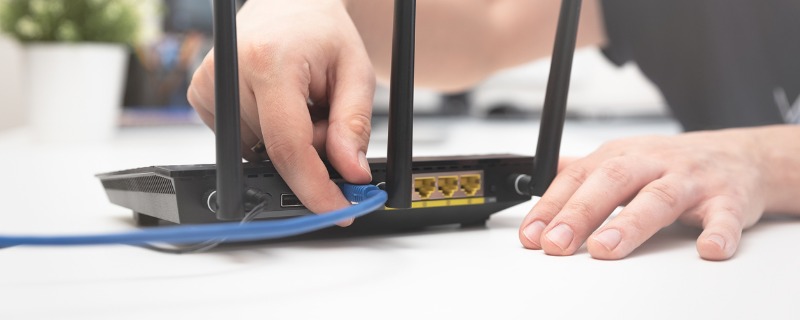 Personne insérant un câble ethernet dans un routeur wifi.