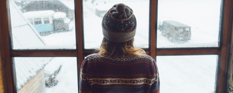  Une jeune fille regarde la neige à l’extérieur de la maison