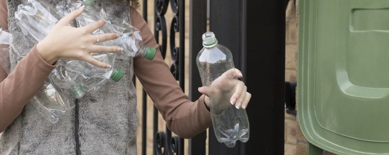 femme mettant des bouteilles en plastique dans un bac de recyclage