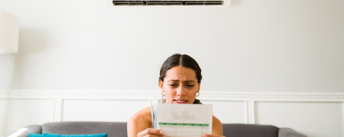 Jeune femme inquiète en recevant la facture d'électricité après avoir utilisé le climatiseur à la maison.