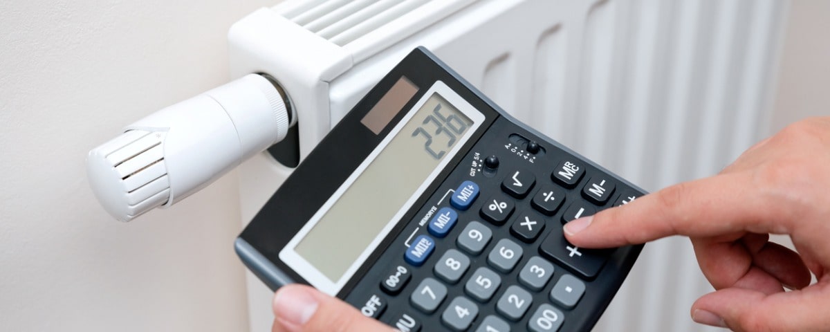 personne avec une calculatrice devant son radiateur, concept de prix de l'énergie élevé 