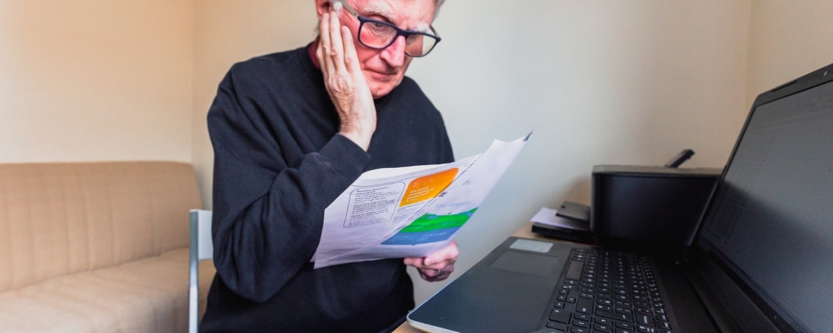 Portrait d'un homme caucasien d'une soixantaine d'années vérifiant ses factures d'énergie à la maison. 