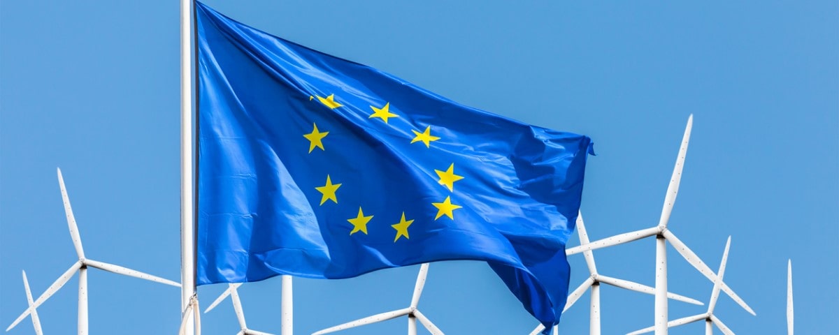 Drapeau officiel de l'Union européenne devant un grand parc d'éoliennes.