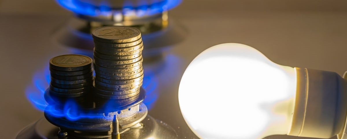 Ampoule allumée à côté d'une cuisinière à gaz allumée, avec des pièces de monnaie à côté. 
