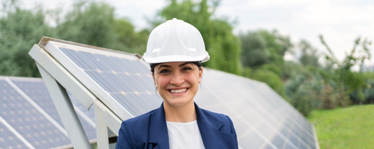 Une femme ingénieur, portant un casque de sécurité, vérifie avec une tablette le fonctionnement d'un système de panneaux solaires dans une station solaire.