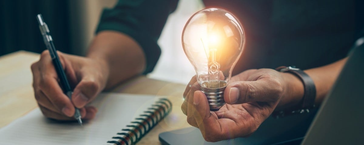 Homme d'affaires tenant une ampoule lumineuse et écrivant un livre. concept d'idée avec innovation et inspiration.