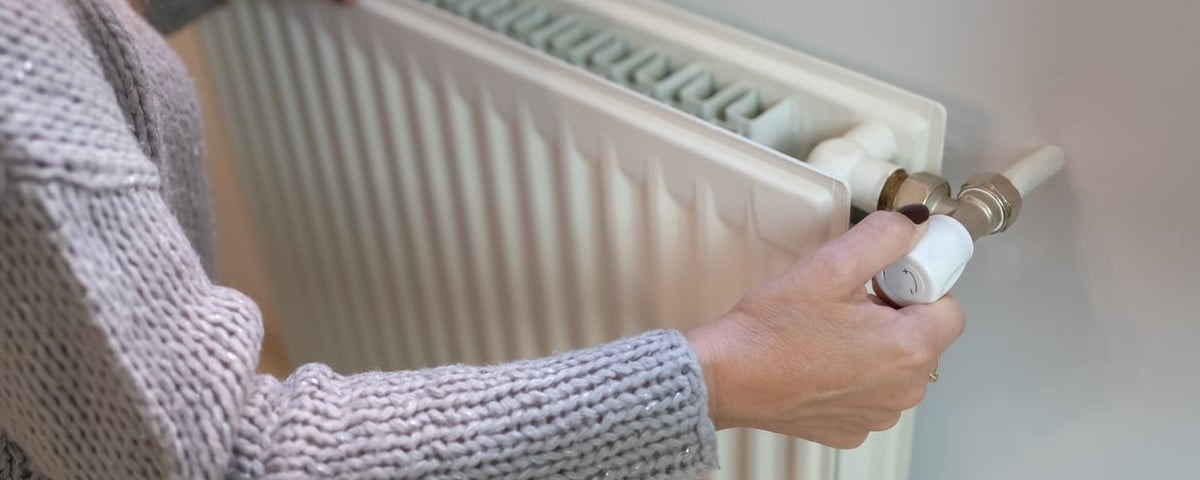 Femme réglant la température d'un radiateur de chauffage, concept de crise énergétique en Europe, augmentation des coûts des ménages privés pour la facture de gaz en raison de l'inflation et de la guerre.