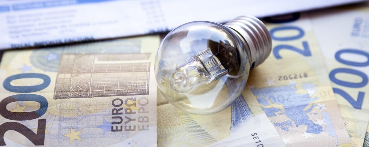 Gros plan sur une ampoule à économie d'énergie et sur des billets de banque en euros
