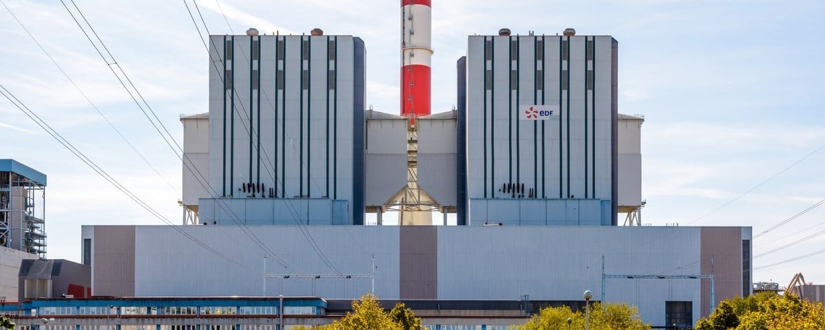 Vue de face du bâtiment principal de la centrale à charbon EDF de Cordemais, avec une cheminée rouge et blanche, près de Nantes, Loire-Atlantique, par une journée ensoleillée.