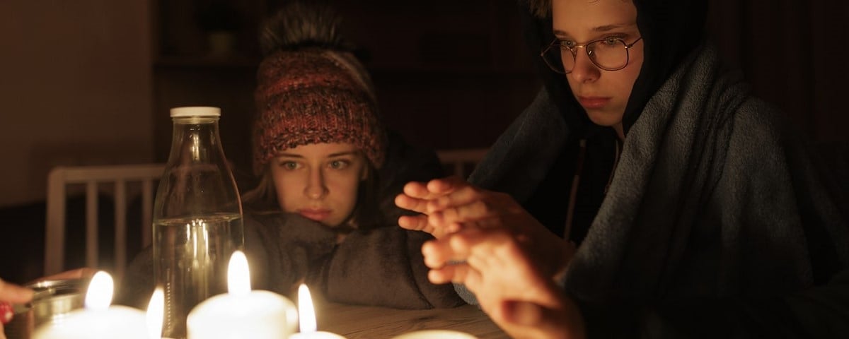Pendant la crise énergétique, la famille est assise à table, éclairée par des bougies.