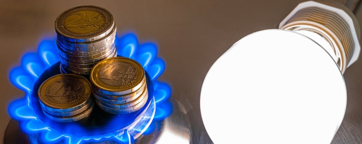 Ampoule allumée et cuisinière à gaz allumée, avec des pièces de monnaie à côté. Coûts de l'énergie et du gaz, augmentation des coûts.