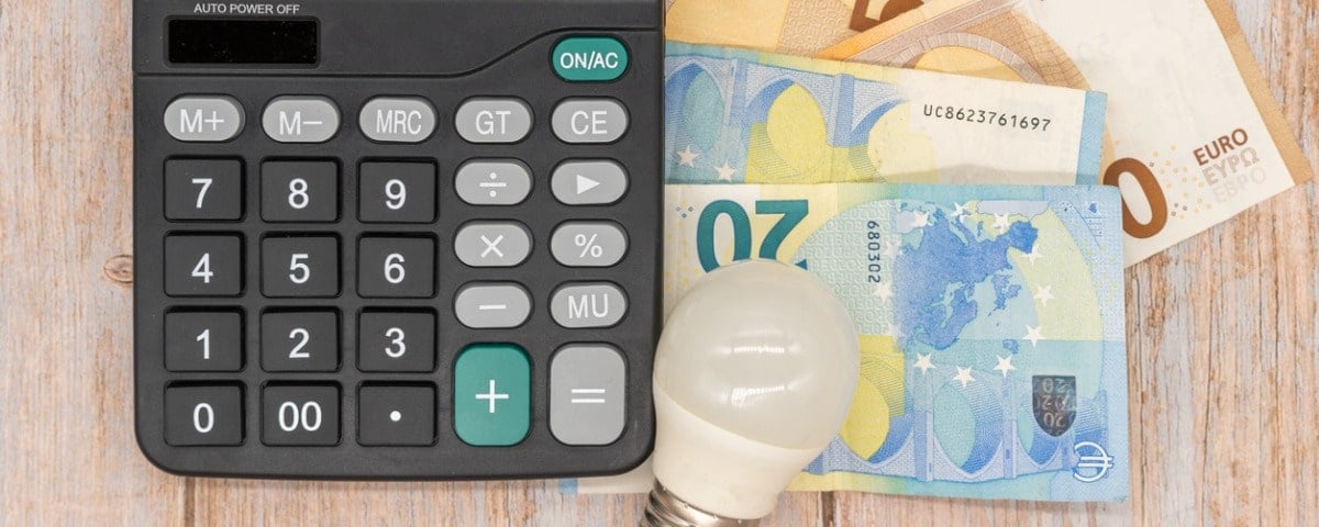 Ampoule, billets de banque en euros, loupe. Augmentation des prix de l'électricité en Europe.