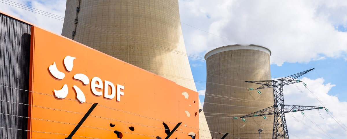 Vue en contre-plongée de l'enseigne EDF (Electricité de France) à l'entrée de la centrale nucléaire de Nogent-sur-Seine et des deux tours de refroidissement.