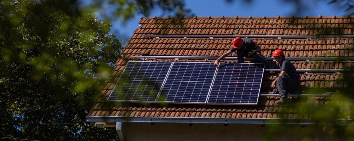 Cols bleus installant des panneaux solaires sur le toit d'une maison