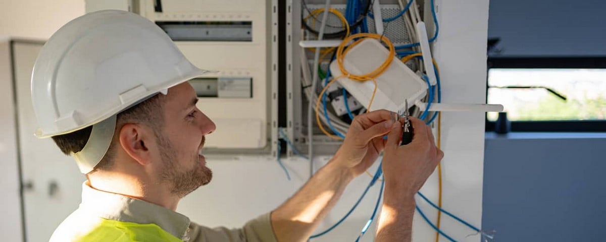 Un jeune électricien caucasien travaille sur une installation internet.