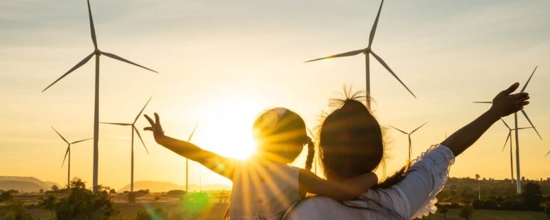 concept de ressources durables, une mère er sa fille de dos observant des éoliennes